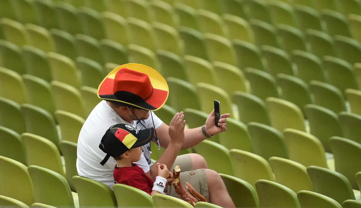 Seorang ayah bersama anaknya melakukan selfie saat menonton laga grup C Euro Cup 2016 antara Jerman melawan Irlandia Utara di Stadion Olympic, Jerman. (21/6/2016). (AFP/Christof Stache)