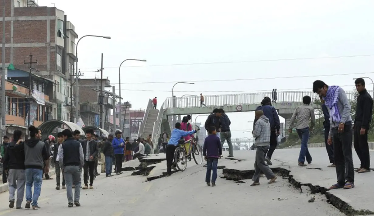 Sejumlah warga Kathmandu melihat jalan yang rusak akibat gempa , Minggu (26/4/2015). Gempa berkekuatan 7,8 Skala Richter dikabarkan telah menelan korban sekitar 2000 jiwa. (AFP Photo/Prakash Mathema)