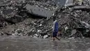 Ribuan orang lainnya masih dinyatakan hilang dan diperkirakan terkubur di bawah reruntuhan. Tampak dalam foto, seorang pria berjalan di tengah banjir di kamp darurat yang menampung warga Palestina yang terlantar setelah hujan deras di Kota Gaza pada Selasa 25 November 2025. (Omar AL-QATTAA/AFP)