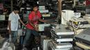 Nurcholis Agi (kiri) bersama pekerjanya saat merapihkan tumpukan barang-barang elektronik bekas disudut ruangan toko Mal Rongsok, Depok, Rabu (17/2). (Liputan6.com/Yoppy Renato)