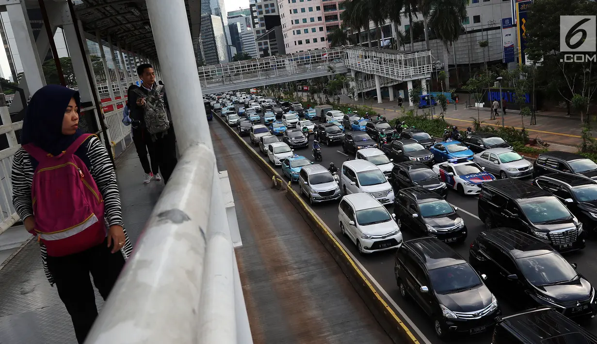 Pejalan kaki melihat kemacetan di Jalan Sudirman-Thamrin, Jakarta, Kamis (20/12). Sejumlah tranportasi multi moda yang sedang dibangun yakni commuter line, MRT, LRT, bus rapid transit (BRT). (Liputan6.com/JohanTallo)