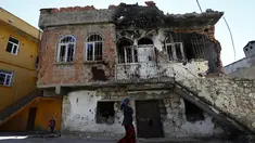 Seorang wanita berjalan melewati bangunan yang rusak akibat konflik antara Militer Turki dan Militan Kurdi di provinsi Diyarbakir, Turki, (7/12). Konflik ini telah terjadi puluhan tahun. (REUTERS/Murad Sezer)