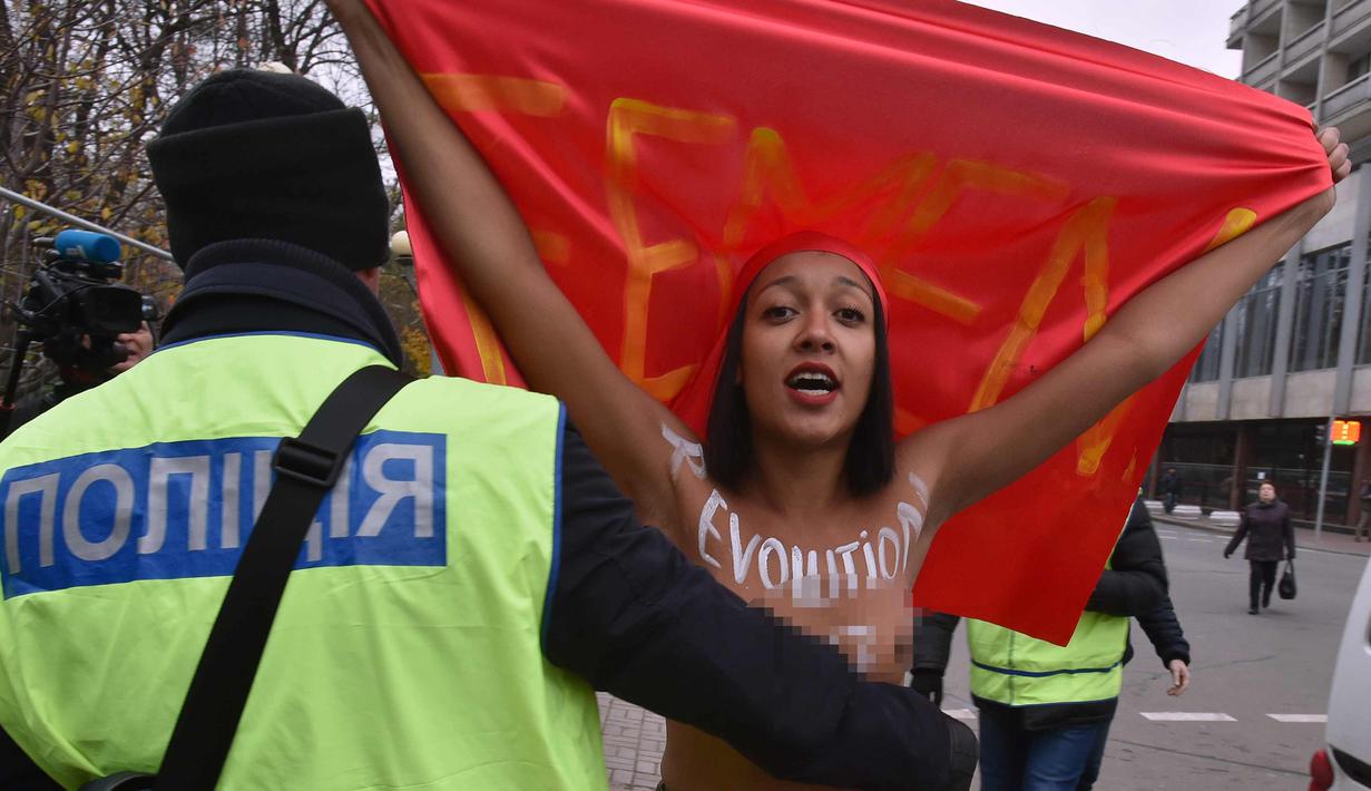 Petugas menghalau aktivis wanita gerakan hak perempuan Femen saat unjuk rasa memperingati 100 tahun Revolusi Bolshevik di pusat kota Kiev, Ukraina (7/11). (AFP Photo/Genya Savilov)