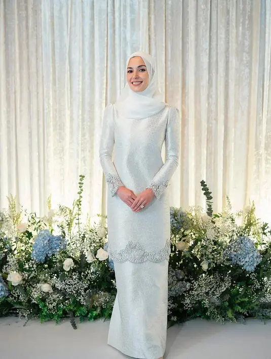 Tampil effortlessly elegan layaknya YM Dayang Anisha Rosnah, dengan mengenakan baju kurung bahan satin warna putih.[@muash.portfolio]