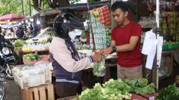 Pedagang melayani pembeli di pasar kawasan Tangerang, Senin (7/2/2022). Ekonom Centre for Strategic and International Studies (CSIS) meminta pemerintah bisa mengantisipasi ketersediaan bahan pokok seiring peningkatan kasus COVID-19 varian Omicron. (Liputan6.com/Angga Yuniar)