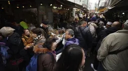 Wisatawan dan warga yang sedang mencari bahan-bahan untuk membuat makanan tahun baru atau osechi memenuhi jalanan Pasar Tsukiji, Tokyo, Jepang, Kamis (26/12/2019). Sebagian besar makanan osechi dimasak sangat manis, asin, atau diacar dengan cuka. (AP Photo/Eugene Hoshiko)