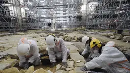Para arkeolog menggali lantai Katedral Notre Dame setelah ditemukannya sarkofagus timah abad ke-14, di Paris (15/3/2022). Penemuan sarkofagus timah tersebut dapat menawarkan wawasan baru tentang sejarah bangunan yang dalam rekonstruksi setelah kebakaran hebat pada tahun 2019.  (AFP/Julien De Rosa)