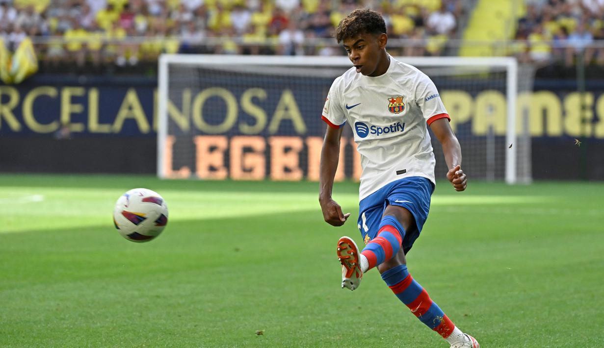 Pemain Barcelona, Lamine Yamal, melepaskan tendangan saat melawan Villarreal pada laga Liga Spanyol 2023/2024 di Stadion La Ceramica, Minggu (27/8/2023). Barca menang dengan skor 4-3. (AFP/Javier Soriano)