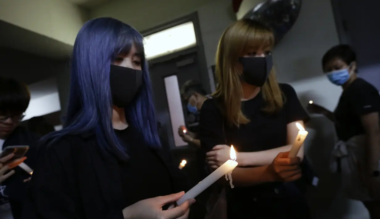 Dua wanita memegang lilin ketika mereka memberi penghormatan kepada mahasiswa Alex Chow Tsz-lok yang tewas di Hong Kong (8/11/2019). Tewasnya Chow memicu kemarahan lebih besar terhadap pihak berwenang di wilayah China semi-otonom. (AP Photo/Dita Alangkara)