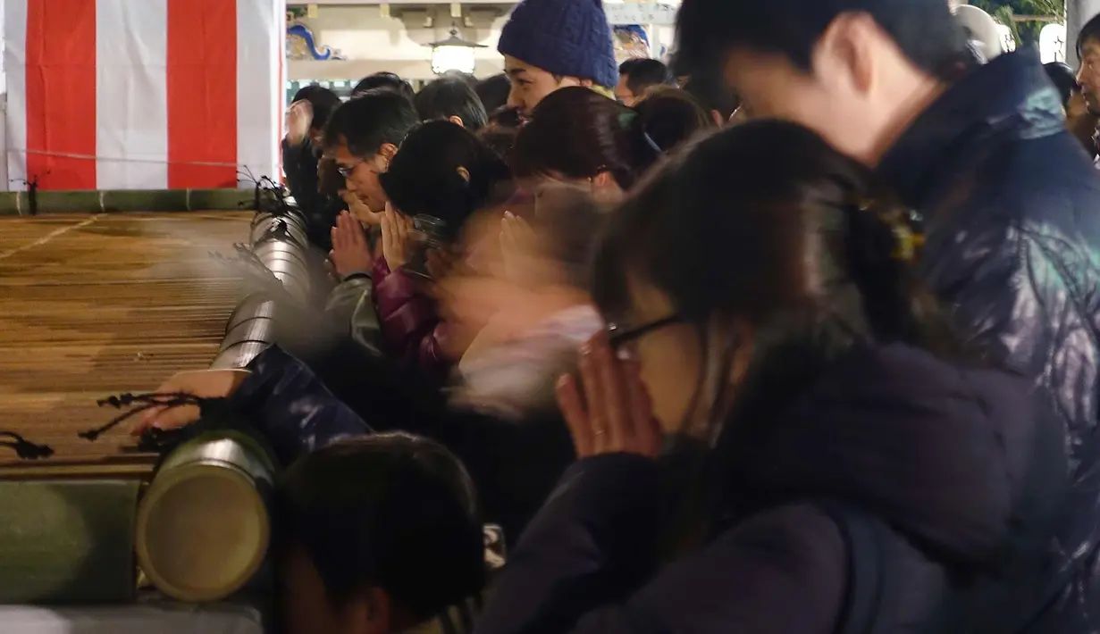 Sejumlah jemaah memanjatkan doa di Kuil Yushima Tenjin di Tokyo, Jepang (1/1). Jepang merayakan dimulainya tahun 2018, Tahun Anjing dalam zodiak Asia. (AP Photo / Eugene Hoshiko)