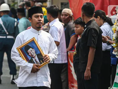 Kerabat membawa foto almarhum Wakil Presiden ke-9 Republik Indonesia, Hamzah Haz di Jalan Tegalan, Matraman, Jakarta, Rabu (24/7/2024). (Liputan6.com/Angga Yuniar)