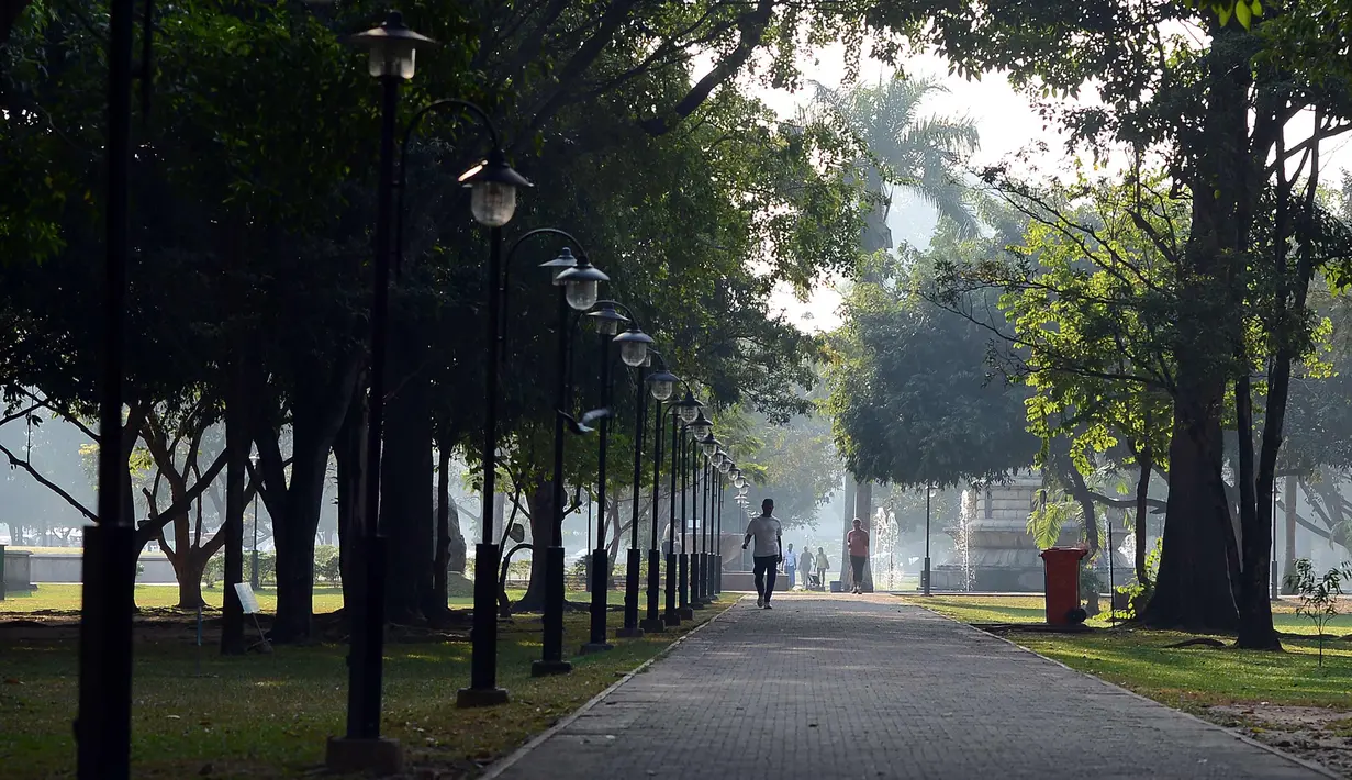 Seorang pria berjalan menikmati suasana Taman Viharamahadevi di Kolombo, Sri Lanka (3/1). Taman ini dibangun selama pemerintahan Britania di Sri Lanka, dan awalnya bernama "Taman Victoria" setelah Ratu Victoria.  (AFP Photo/Lakruwan Wanniarachchi)