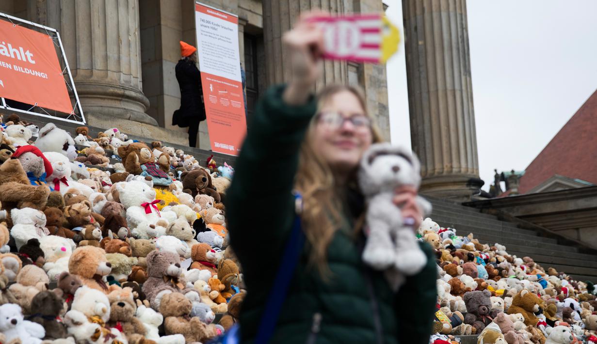 Seorang siswa berswafoto sebelum meletakkan boneka beruang atau Teddy Bears di tangga Concert Hall, Berlin, Kamis (15/3). 740 boneka itu dipajang di tengah kegiatan Organisasi Visi Dunia yang memiliki tujuan misi kemanusiaan. (AFP PHOTO/Odd ANDERSEN)