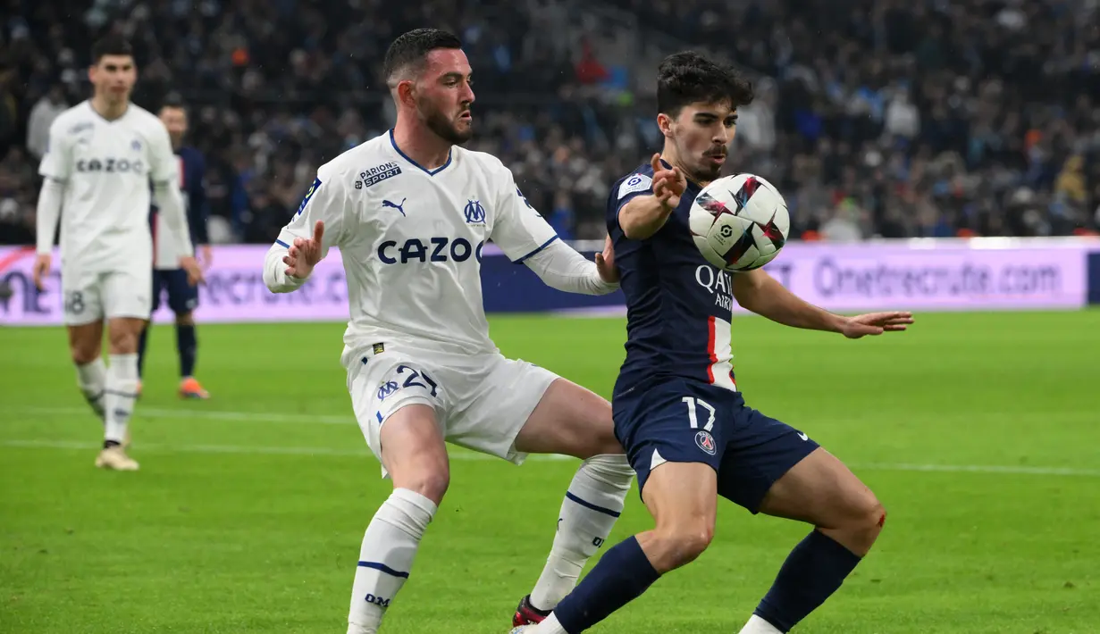 Gelandang Paris Saint-Germain (PSG) Vitinha berebut bola dengan gelandang Marseille Jordan Veretout dalam laga pekan ke-25 Liga Prancis 2022-2023, di Stadion Velodrome pada Senin (27/2/2023) dini hari WIB. Hasil ini membuat PSG bisa menjauh dari kejaran Marseille di klasemen sementara Liga Prancis musim 2022-2023.  (Photo by NICOLAS TUCAT / AFP)