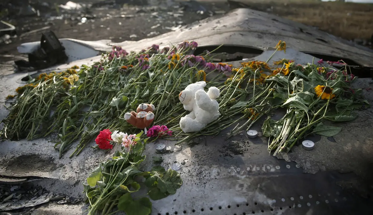 Untaian bunga dan mainan anak diletakkan di salah satu sisa badan pesawat Malaysia Airlines MH-17 yang jatuh dan terbakar di Donetsk, Ukraina, (19/7/2014). (REUTERS/Maxim Zmeyev)