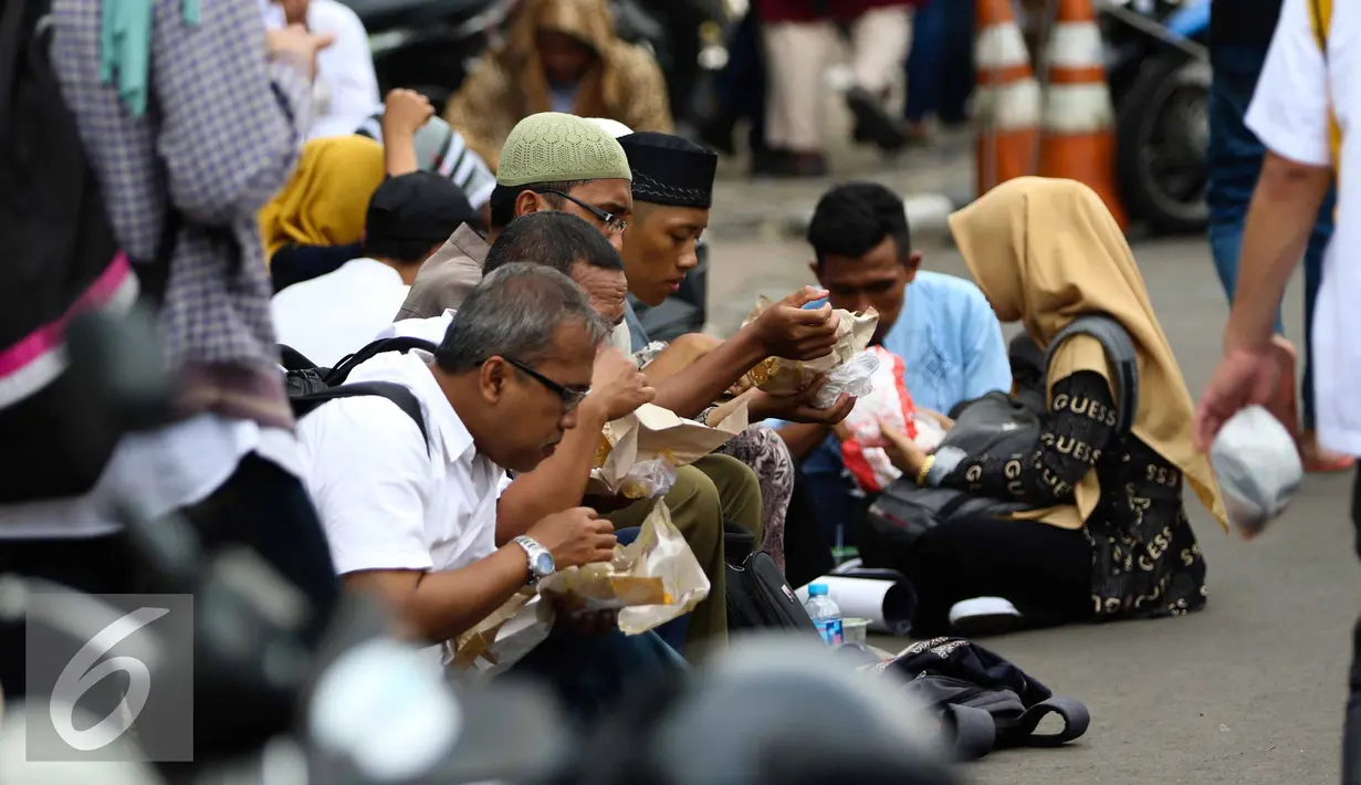 Sejumlah massa aksi makan siang sebelum memulai aksi di Medan Merdeka Timur, Jakarta, Jumat (4/11). Massa melakukan aksi di depan Istana Negara menuntut penegakan hukum kasus dugaan penistaan agama. (Liputan6.com/Faizal Fanani)