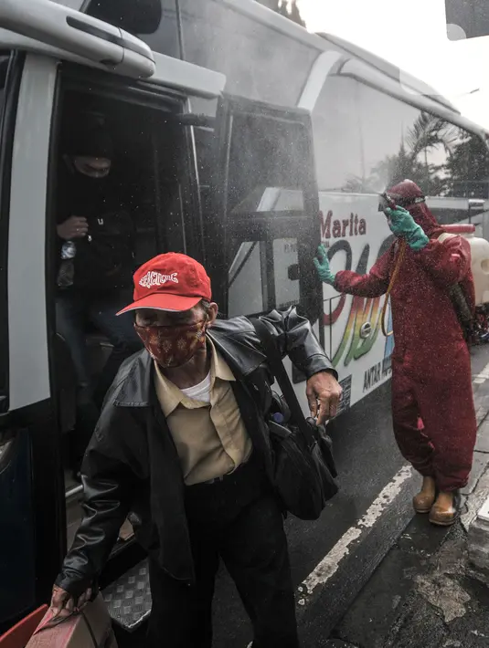 Petugas pemadam kebakaran menyemprotkan disinfektan kepada penumpang bus AKAP di Terminal Kampung Rambutan, Jakarta, Minggu (23/5/2021). Penyemprotan rutin dilakukan kepada bus AKAP dan penumpang selama arus mudik Lebaran sebagai langkah mencegah penyebaran Covid-19. (merdeka.com/Iqbal S Nugroho)