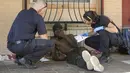 <p>Petugas Layanan Medis Darurat Austin-Travis Kapten Darren Noak (kiri) dan M. Megally memeriksa seorang pria saat peringatan panas berlebihan ketika suhu mencapai 107 derajat di East 6th Street di Austin, Texas, Amerika Serikat, 12 Juli 2023. Pria itu kemudian diangkut menggunakan ambulans ke rumah sakit karena masalah terkait panas. (Jay Janner/Austin American-Statesman via AP)</p>