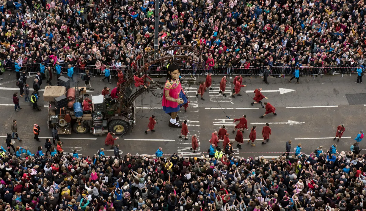 Sebuah boneka raksasa bernama Little Girl Giant melintasi jalan sepanjang dermaga di Liverpool, Inggris, Minggu (7/10). Boneka itu karya dari kelompok teater jalanan Prancis, Royal de Luxe dengan ciri khas aktor berupa Boneka Super Besar. (OLI SCARFF/AFP)