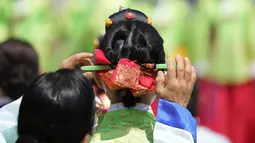 Seorang wanita menata rambut gadis muda saat upacara untuk menghidupkan kembali Hari Kedewasaan ke-50 di Desa Hanok Namsangol di Seoul, Korea Selatan (16/5/2022). Upacara diadakan untuk pria dan wanita muda yang akan berusia 20 tahun. (AP Photo/Lee Jin-man)