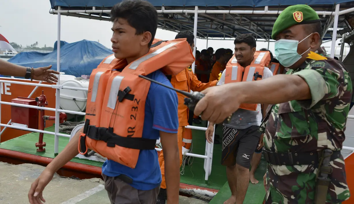 Personel TNI memandu sukarelawan yang bertindak sebagai pengungsi selama simulasi penyelamatan pengungsi luar negeri di perairan Banda Aceh, Kamis (17/10/2019). Kegiatan diikuti unsur TNI, Polri, relawan dan pimpinan lembaga peduli bencana di Aceh. (CHAIDEER MAHYUDDIN/AFP)