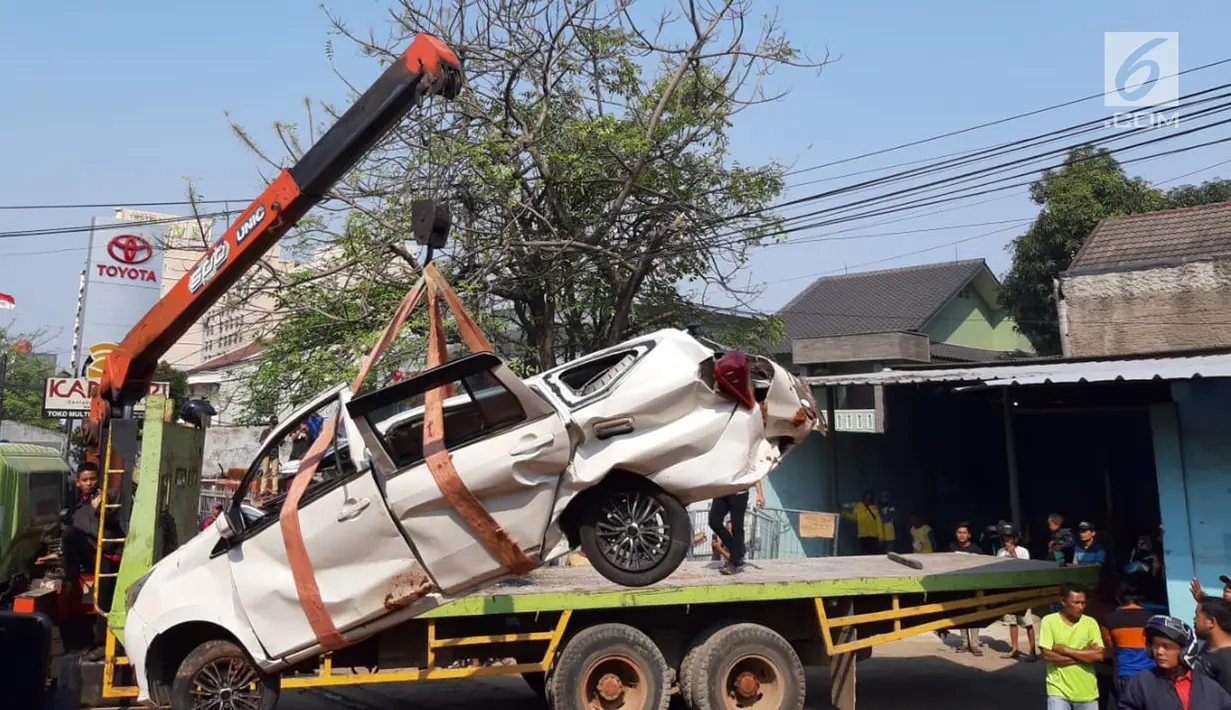 Petugas derek mengevakuasi bangkai mobil kecelakaan maut yang hancur tertindih badan truk muatan tanah di Karawaci, Tangerang, Kamis (1/8/2019). Lima orang penumpang minibus menjadi korban, empat diantaranya meninggal dan satu balita berhasil diselamatkan warga. (Liputan6.com/Pramita Tristiawati)