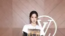 Ouyang Nana mengenakan atasan t shirt putih dipadukan inner lace serta belt besar hitam senada dengan warna celana panjangnya. Membawa tas warna beige. [dok. Louis Vuitton]