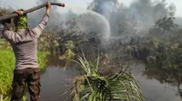 Polisi menyemprotkan air ke kebakaran lahan agar apinya tak meluas dan menimbulkan bencana kabut asap. (Liputan6.com/M Syukur)