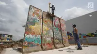 Seniman Teguh Ostenrik (kanan) mengawasi pemasangan pecahan Tembok Berlin dan Patung Menembus Batas di RPTRA Kalijodo, Jakarta, Selasa (26/9). Hal ini bertujuan agar masyarakat bisa melihat langsung tembok bersejarah itu. (Liputan6.com/Immanuel Antonius)