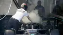 Kondisi mobil dari pembalap Mercedes, George Russell yang terus menerus mengeluarkan asap putih dari bagian mesin saat dibawa oleh mekanik menuju garasi. (AFP/Pool/Simon Baker)