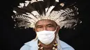 Pemimpin adat dari etnis Mura, Pedro dos Santos memakai pakaian tradisional dan masker saat pandemi virus corona COVID-19 di Taman Bangsa Adat, Manaus, Brasil, Kamis (28/5/2020). Pada bulan April, dos Santos, istri, anak-anak, dan cucunya jatuh sakit dengan gejala COVID-19. (AP Photo/Felipe Dana)