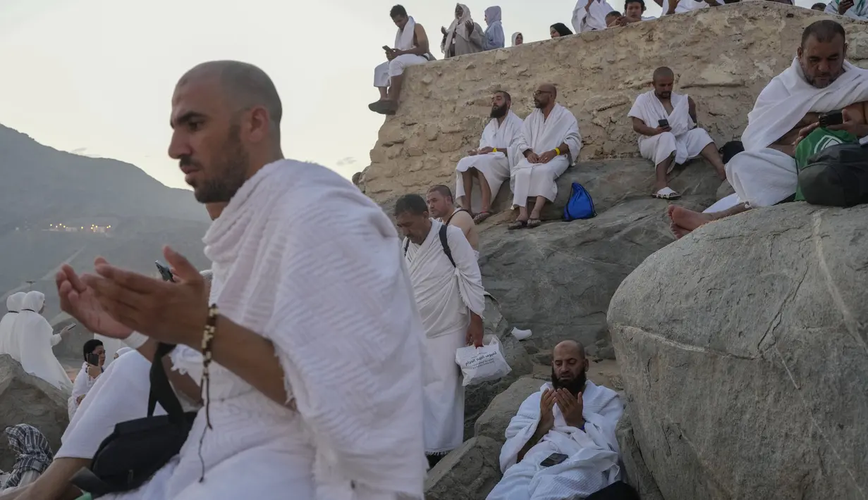 Umat muslim berdoa di puncak bukit berbatu yang dikenal sebagai Gunung Rahmat di Dataran Arafah saat menunaikan ibadah haji dekat Kota Suci Makkah, Arab Saudi, Sabtu (15/6/2024). (AP Photo/Rafiq Maqbool)