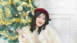 Begini potret Anneth Delliecia saat melalukan pemotretan dengan tema Natal. Berpose di samping pohon natal besar dengan kenakan jaket berbahan bulu dipadukan dengan topi, Anneth begitu memesona. (Liputan6.com/IG/@fdphotography90)
