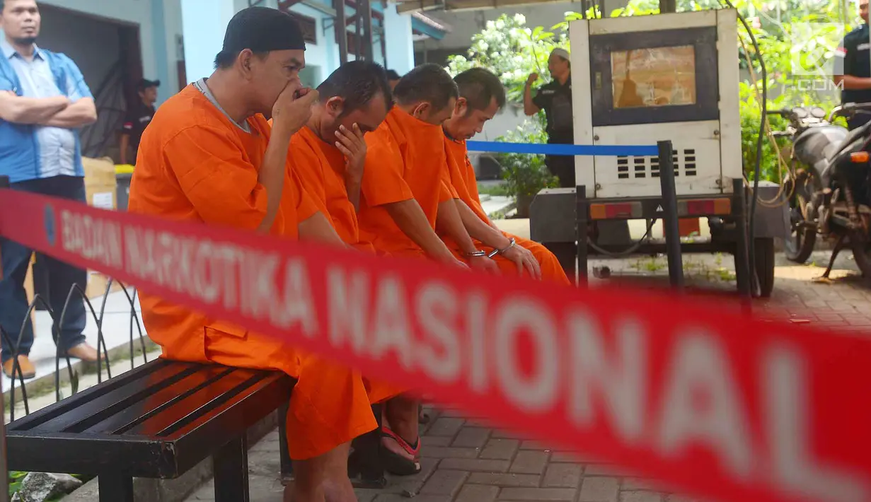 Para tersangka tertunduk saat Badan Narkotika Nasional (BNN) melakukan pemusnahan barang bukti narkoba jenis sabu, Jakarta, Kamis (26/7). Barang bukti sabu seberat 20,42 Kilogram dimusnahkan dengan cara dibakar. (Merdeka.com/Imam Buhori)
