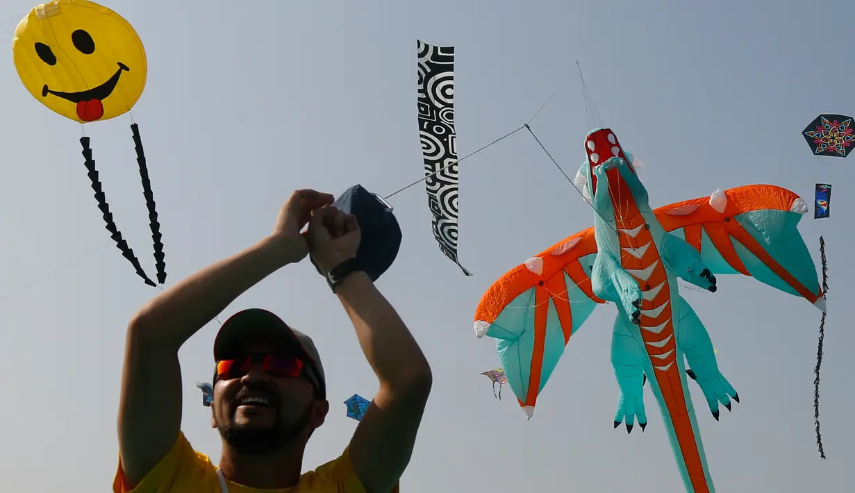 Seorang peserta menerbangkan layang-layang berbentuk naga saat festival layang-layang Internasional di Ahmadabad, India (7/1). Acara ini menarik banyak penonton dari India dan negara lainnya. (AP Photo/Ajit Solanki)