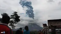Warga menyaksikan gumpalan asap yang membumbung tinggi ke langit saat Gunung Sinabung memuntahkan uapnya. (AFP/Stringer/wwn)