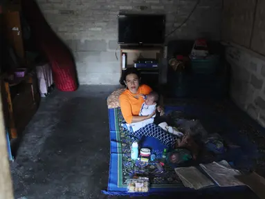 Seorang ibu menggendong sang anak saat santai di rumahnya dusun Regahan Lada, Pulau Sebesi, Lampung, Senin (31/12). Banyak warga dusun ini yang bertahan di lokasi pascatsunami yang melanda Selat Sunda pada 22 Desember lalu. (Liputan6.com/Herman Zakharia)