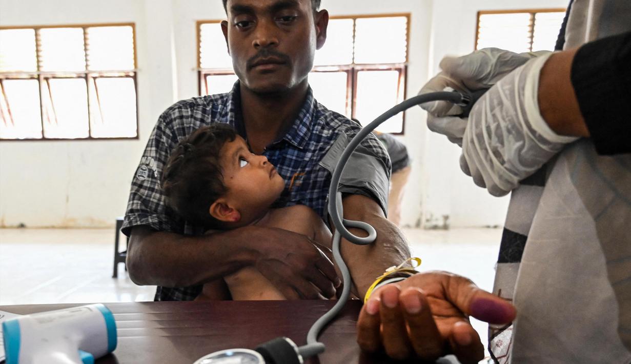 Seorang pengungsi Rohingya dan anaknya menerima pemeriksaan kesehatan di tempat penampungan sementara di Ladong, provinsi Aceh, Jumat 24 Februari 2023. Sedikitnya 69 pengungsi Rohingya mendarat di pantai barat Indonesia pada 16 Februari lalu dengan sebuah perahu kayu, kata seorang pejabat badan pengungsi PBB. (CHAIDEER MAHYUDDIN/AFP)Seorang pengungsi Rohingya menjemur pakaiannya di tempat penampungan sementara di Ladong, Provinsi Aceh, Jumat 24 Februari 2023. Puluhan imigran Rohingya tersebut berlayar dengan kapal kayu berukuran 15x4 meter dan terdampar di pesisir pantai tepatnya di Desa Lampanah Leungah Kecamatan Seulimum, Kabupaten Aceh Besar, Kamis (16/2) lalu. Dari hasil pendataan 69 pengungsi Rohingya tersebut terdiri dari laki-laki dewasa 26 orang, perempuan dewasa 23, dan anak-anak 20 orang. (CHAIDEER MAHYUDDIN/AFP)