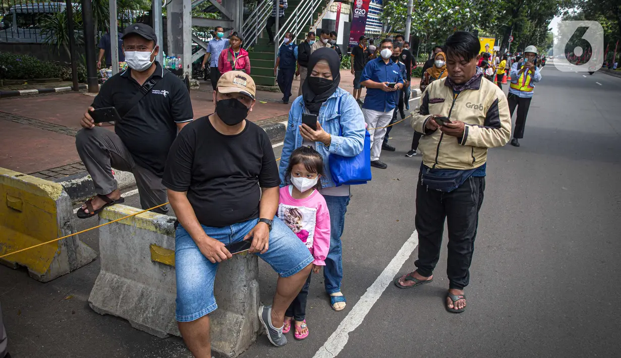 Warga menunggu parade pembalap MotoGP di kawasan Jakarta, Rabu (16/3/2022).  Gelaran parade MotoGP di Jakarta dalam rangka penyambutan event MotoGP Mandalika 2022. (Liputan6.com/Faizal Fanani)