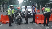 Sejumlah aparat kepolisian memeriksa pengendara yang melintas di Jalan Asia Afrika, Kota Bandung, saat diberlakukannya Pembatasa Sosial Berskala Besar (PSBB), Rabu (22/4/2020). (Liputan6.com/Huyogo Simbolon)