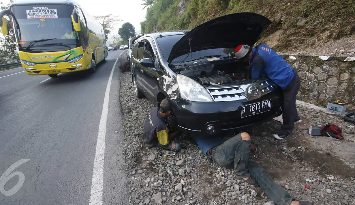 Montir memperbaiki mobil yang rusak di Jalan Warung Peuteuy, Garut, Jabar, Senin (4/7). Banyaknya kendaraan pemudik yang rusak menjadi berkah bagi para montir panggilan dengan pendapatan hingga 4x lipat dibanding biasa. (Liputan6.com/Immanuel Antonius)