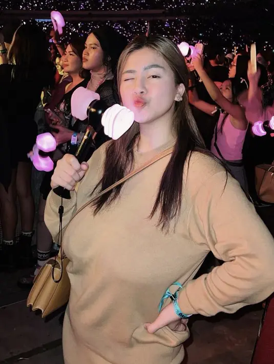 Sambil membawa light stick, Felicya tampil dengan atasan lengan panjang yang serasi dengan sling bagnya.  (@felicyangelista_)