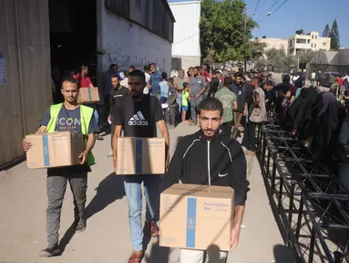 Warga Palestina mengangkat kotak bantuan dari Program Pangan Dunia (WFP) di pusat distribusi di desa Al-Zawayda, di tengah-tengah Jalur Gaza, pada 27 Oktober 2025. (BASHAR TALEB/AFP)