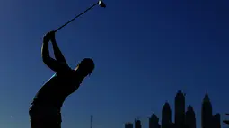 Siluet pegolf Inggris, Danny Willett, saat memukul bola dalam turnamen golf Dubai Desert Classic 2016 di Emirates Golf Club, Dubai, (7/2/2016). (AFP/Karim Sahib)