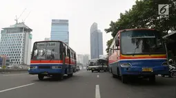 Bus Kopaja dan Metromini melintas di Jalan Jenderal Sudirman, Jakarta, Rabu (4/7). Larangan bagi Kopaja dan Metromini melintasi jalan protokol selama Asian Games untuk mengurangi kemacetan dan polusi di jalan protokol. (Liputan6.com/Arya Manggala)