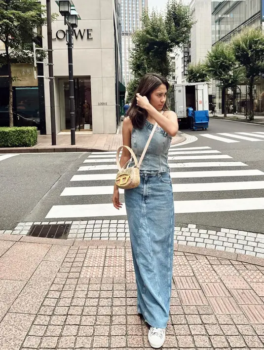 Denim on denim style dari atasan asimetris dan rok panjang jadi salah satu gaya yang patut dicoba. Permanis gaya dengan sling bag mungil! [Instagram/azizahsalsha_]
