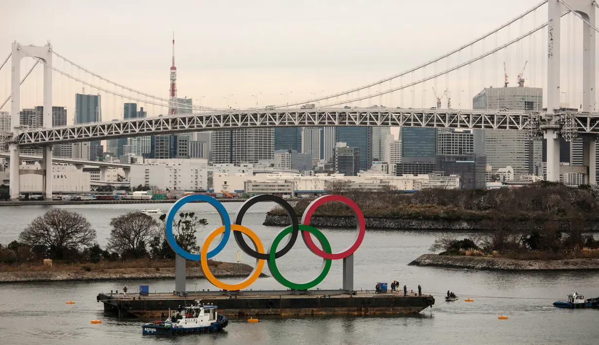 Kapal tongkang membawa Cincin Olimpiade dekat Rainbow Bridge di Distrik Odaiba, Tokyo, Jepang, Jumat (17/1/2020). Cincin Olimpiade dengan tinggi 15,3 meter dan panjang 32,6 meter tersebut akan berada di sana hingga Olimpiade 2020 berakhir. (AP Photo/Jae C. Hong)