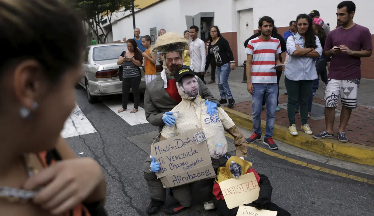  Patung yang dipasang gambar Presiden Venezuela Nicolas Maduro (atas) saat akan dibakar oleh warga di Caracas , Venezuela, (27/3). Hal ini dilakukan dalam perayaan Paskah di Caracas. (REUTERS / Marco Bello)