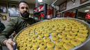 Kudapan manis itu berbentuk bulat, diisi dengan kurma atau kenari, pistachio dan kacang-kacangan. Lapisan luarnya ditaburi gula putih halus. (Photo by AHMAD GHARABLI / AFP)