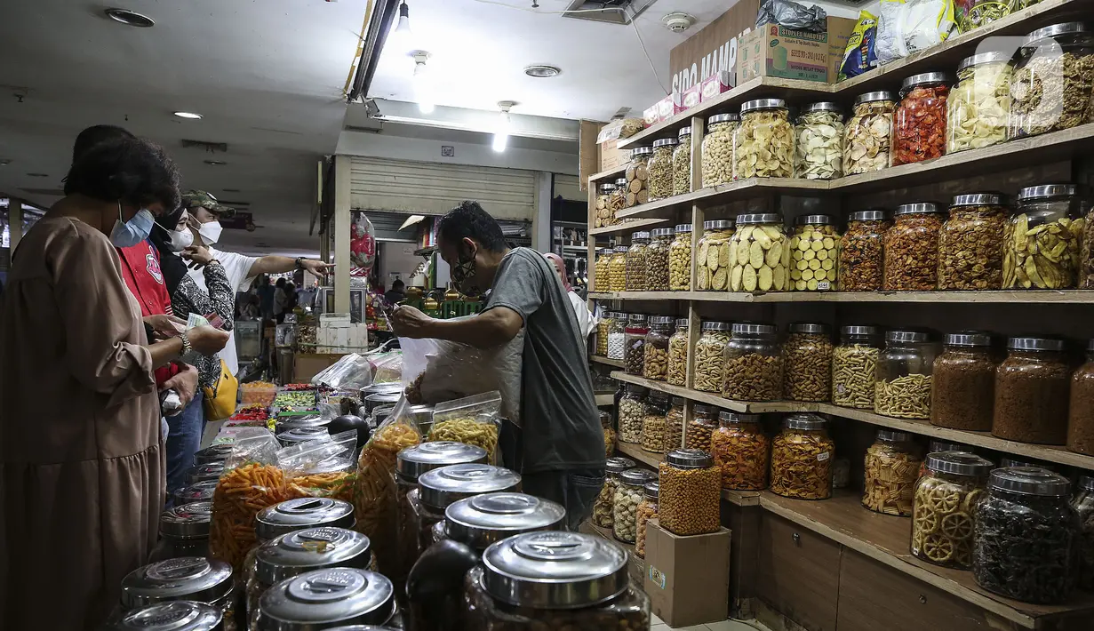 Pedagang kue kering melayani pembeli di Pasar Mayestik, Jakarta, Senin (3/5/2021). Omzet penjualan kue kering menjelang Lebaran tahun ini mengalami peningkatan hingga 70 persen dari tahun sebelumnya yang mengalami penurunan hingga 70 persen. (Liputan6.com/Johan Tallo)